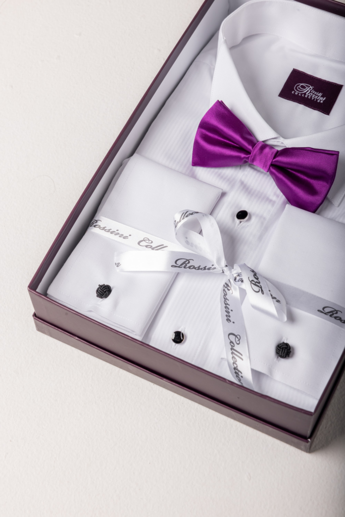 Dress shirt, cufflinks and a magenta bow tie laid out in a box